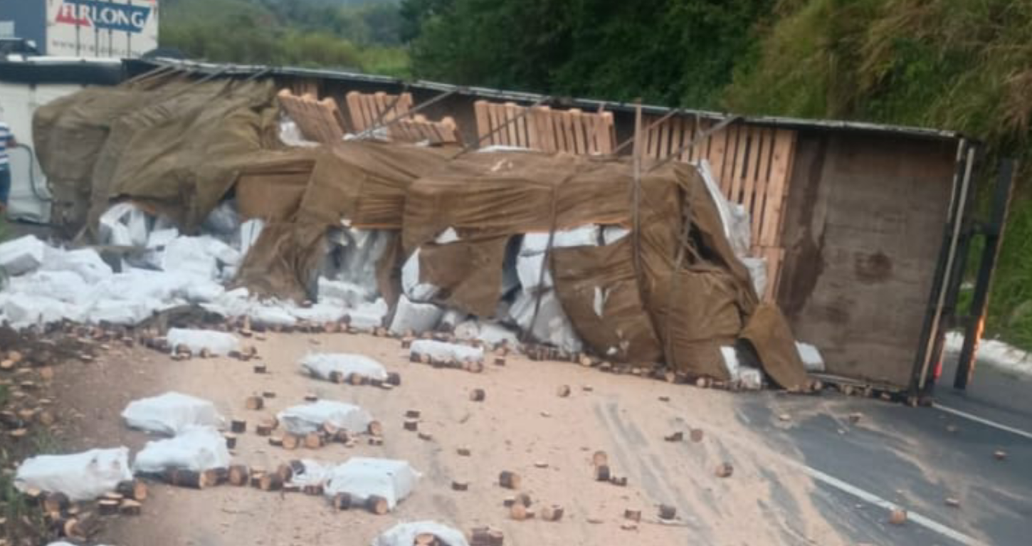 Carreta com madeira tomba, derrama carga e causa interdição de pista na Régis Bittencourt 